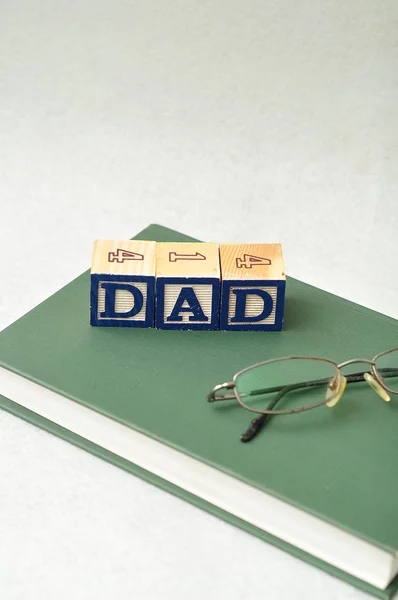 Papai soletrado com blocos coloridos com um livro e óculos — Fotografia de Stock