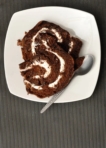 Chocolate swiss roll displayed on a white plate — Stock Photo, Image