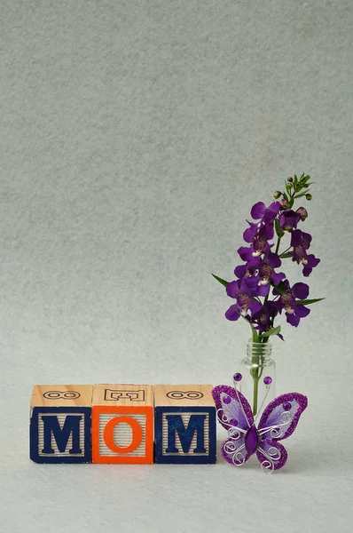 Maman orthographiée avec des blocs d'alphabet et de petites fleurs violettes — Photo