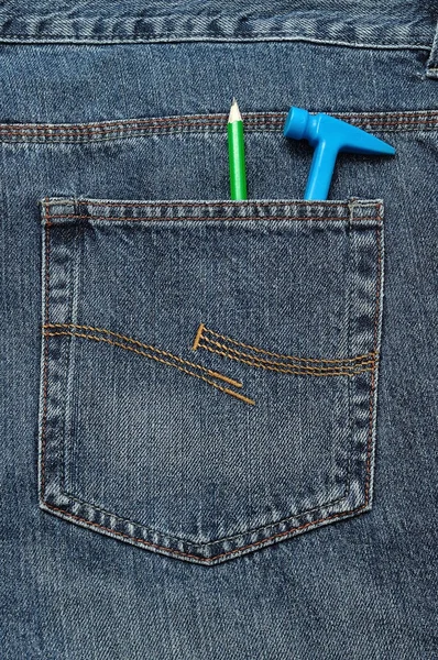 Ein Spielzeug-Plastik-Hammer in der Gesäßtasche einer Jeans mit Bleistift — Stockfoto