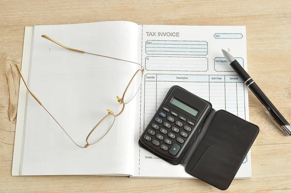 Calculadora, caneta, óculos e livro de faturas — Fotografia de Stock
