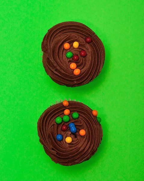 Dois cupcakes de chocolate isolados em um fundo verde — Fotografia de Stock