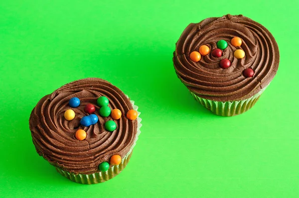 Dois cupcakes de chocolate isolados em um fundo verde — Fotografia de Stock