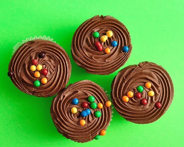 Quatro cupcakes de chocolate isolados em um fundo verde — Fotografia de Stock