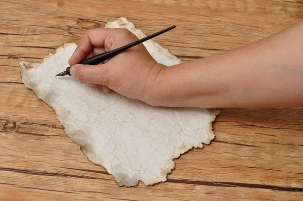 Una mano sosteniendo un bolígrafo negro vintage sobre un pedazo de viejo — Foto de Stock