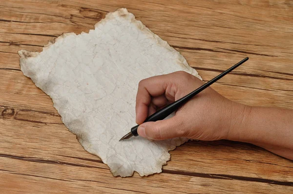 Una mano sosteniendo un bolígrafo negro vintage sobre un pedazo de viejo — Foto de Stock