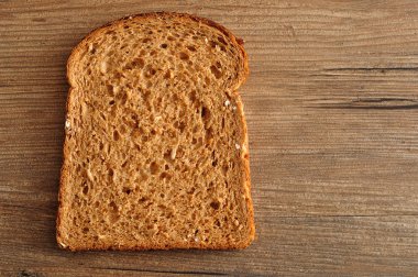 Bir dilim kepekli ekmek ahşap bir masa üzerinde görüntülenen