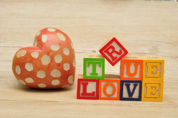 Amor verdadero deletreado con bloques coloridos del alfabeto y un corazón rojo — Foto de Stock