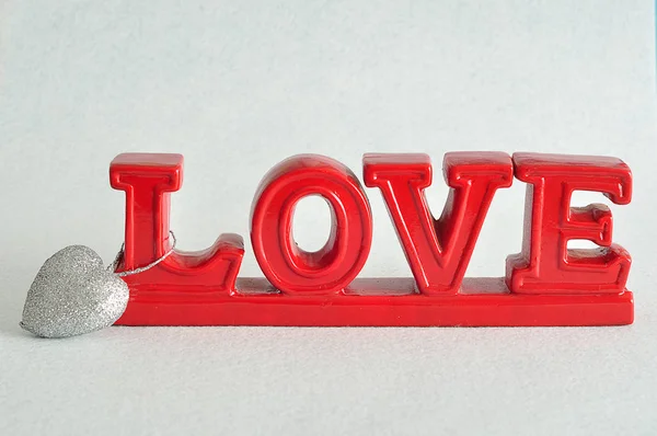 Слово "любов" червоного кольору зі срібною вадою у формі серця, прикріпленою до L — стокове фото