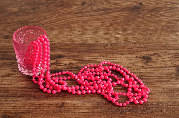 Strings of pink beads displayed in a fancy glass vase — Stock Photo, Image