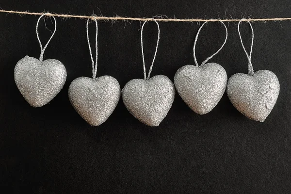 Día de San Valentín. Una fila de corazones de plata colgando de una cuerda — Foto de Stock