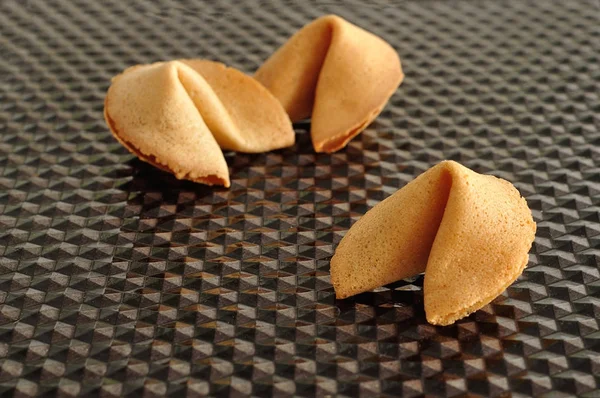 Three fortune cookies displayed on a black background — Stock Photo, Image