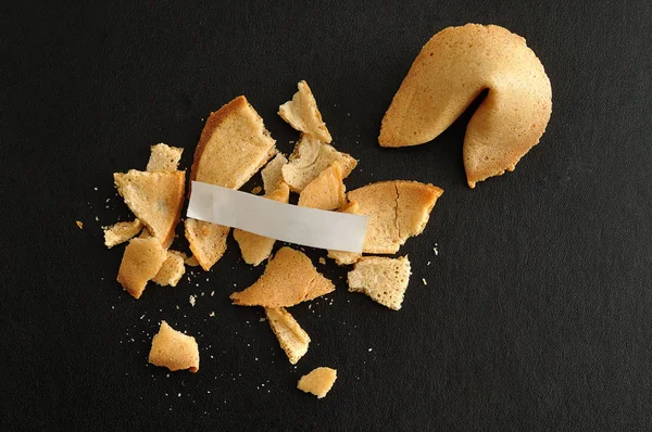 Una galleta de la fortuna rota con un pedazo de papel — Foto de Stock