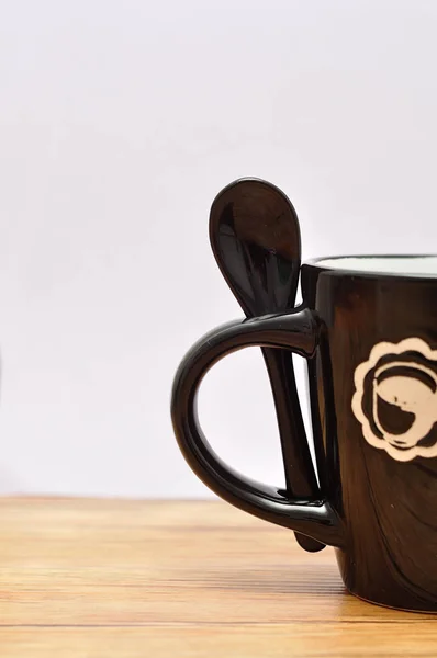 A black mug with a black teaspoon — Stock Photo, Image