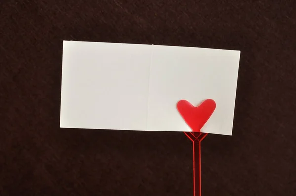 De dag van Valentijnskaarten. De houder van een opmerking met een rood hart met een notitie — Stockfoto