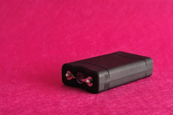 Un taser negro aislado sobre un fondo rosa — Foto de Stock