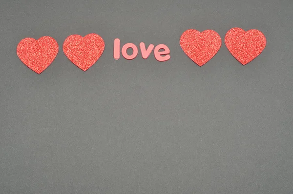 Das Wort Liebe auf schwarzem Hintergrund mit Herzen verziert — Stockfoto