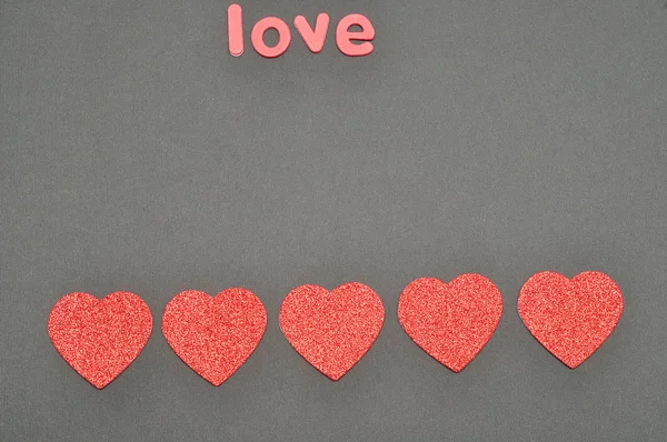Słowo miłość na czarnym tle ozdobione serca — Zdjęcie stockowe