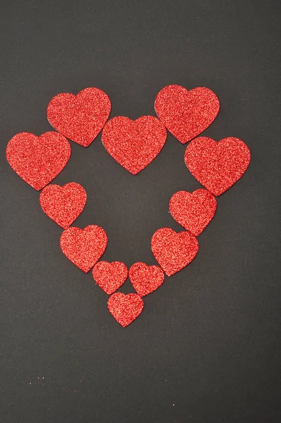 Um coração feito de corações de tamanho diferente em um fundo preto — Fotografia de Stock