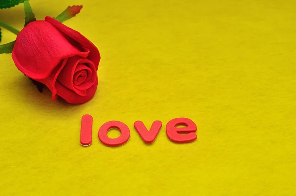 단어 사랑과 노란 배경에 빨간 장미 — 스톡 사진