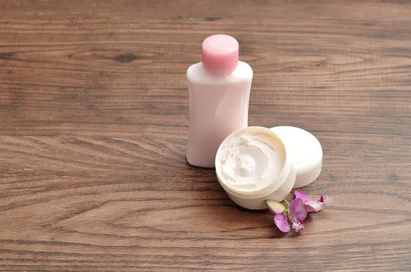 A tub of hand lotion displayed with a small pink bottle of lotio