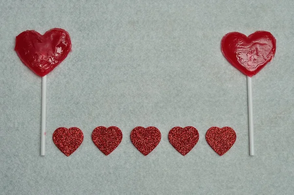 Dois pirulitos em forma de coração exibidos com uma fileira de corações brilhantes — Fotografia de Stock