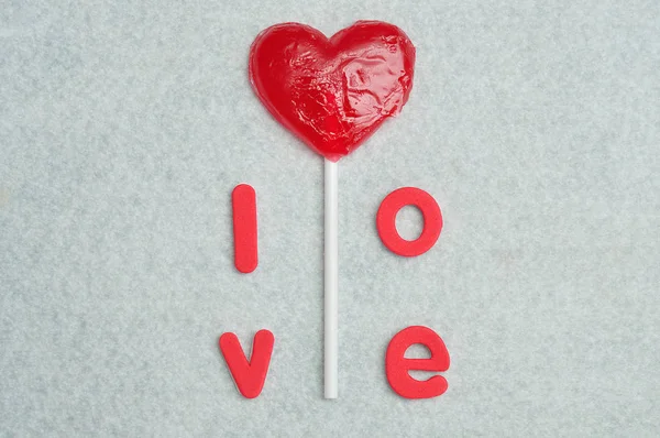 Um pirulito em forma de coração com a palavra amor — Fotografia de Stock