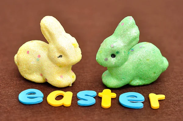 A palavra Páscoa com um coelho amarelo e um coelho verde — Fotografia de Stock