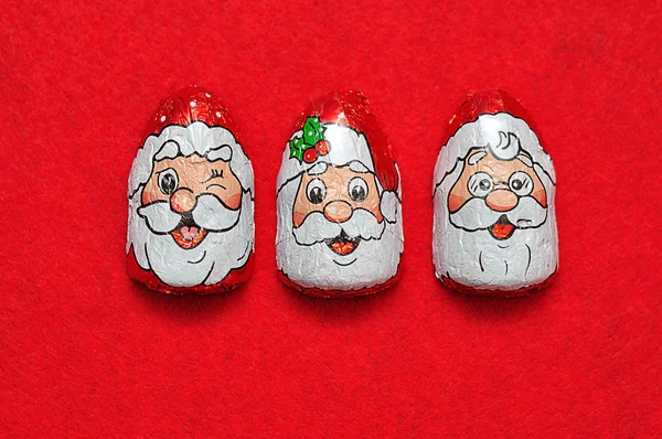 A row of chocolates covered with Santa Claus's face wrappers — Stock Photo, Image