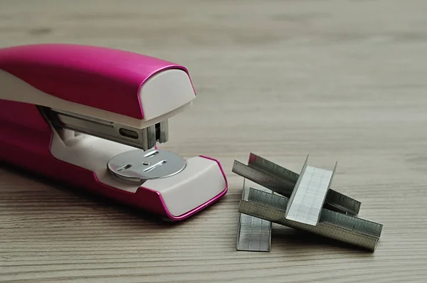 A pink stapler with a pile of staplers on a table — Stock Photo, Image