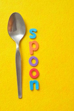Sarı bir arka plan üzerine bir kaşık ile görüntülenen sözcük kaşık
