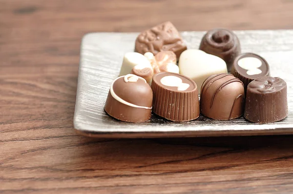 Uma variedade de pequenos chocolates exibidos em uma bandeja de prata — Fotografia de Stock