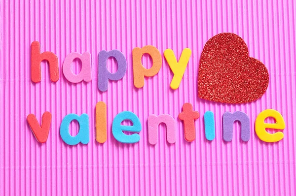 Fröhlicher Valentinstag in bunten Buchstaben auf rosa Hintergrund mit rotem Herz — Stockfoto