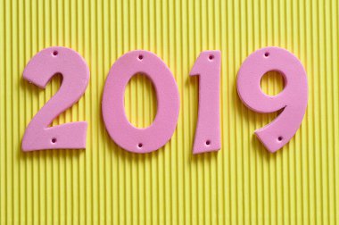 Sarı bir arka plan üzerinde pembe rakamlarla 2019
