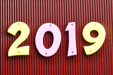 kahverengi bir arka plan üzerine pembe ve sarı rakamlarla 2019