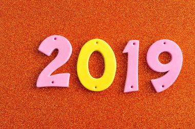 turuncu bir arka plan üzerine pembe ve sarı rakamlarla 2019