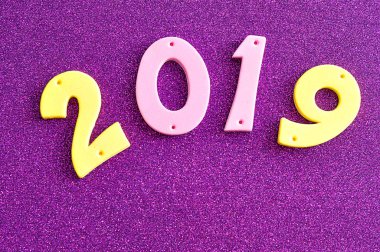 mor bir arka plan üzerine pembe ve sarı rakamlarla 2019