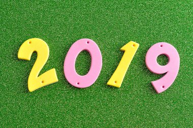 yeşil bir arka plan üzerine pembe ve sarı rakamlarla 2019