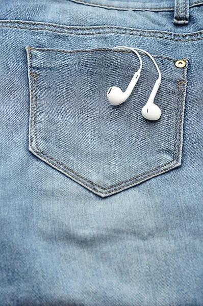 White earphones in the back pocket of a denim Stock Image