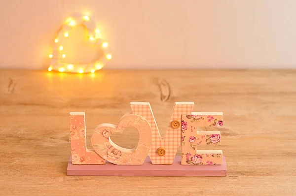 The word love in pink with an out of focus light heart shape