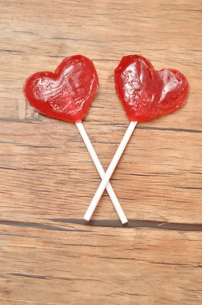 Dua bentuk hati merah lollipop terisolasi dengan latar belakang kayu — Stok Foto
