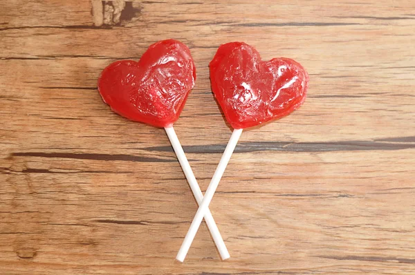 Dois pirulito forma coração vermelho isolado contra um fundo de madeira — Fotografia de Stock
