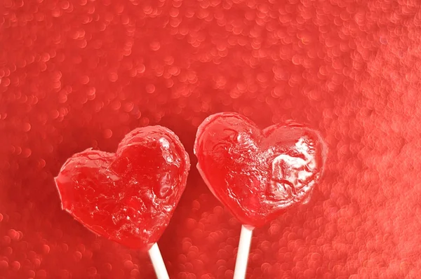 Two red heart shape lollipop isolated against a red background Royalty Free Stock Photos