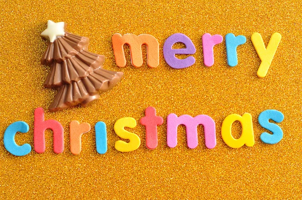 Uma árvore de Natal de chocolate com as palavras Feliz Natal em um fundo dourado — Fotografia de Stock