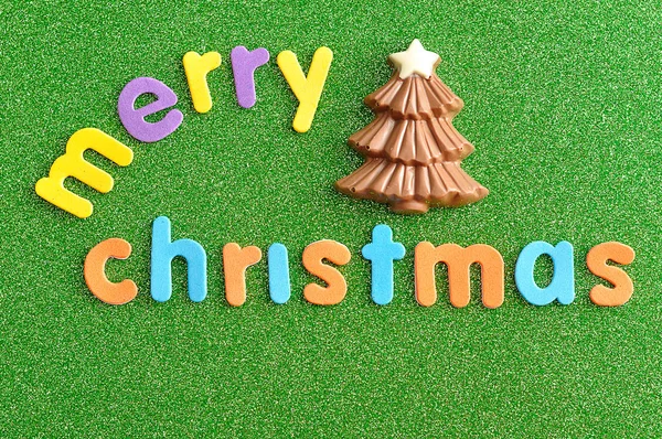 Uma árvore de Natal de chocolate com as palavras Feliz Natal em um fundo verde — Fotografia de Stock