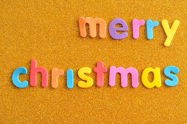 Feliz Natal em letras coloridas sobre um fundo dourado — Fotografia de Stock
