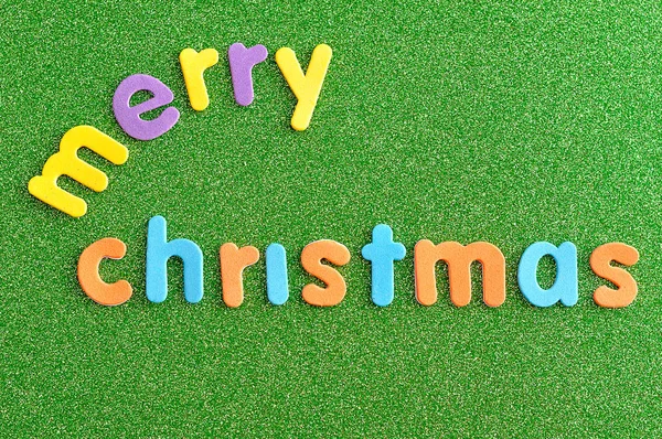 Feliz Natal em letras coloridas sobre um fundo verde — Fotografia de Stock