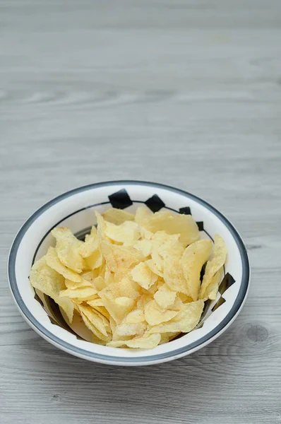 A bowl of crisps on a wooden table — Stock Photo, Image