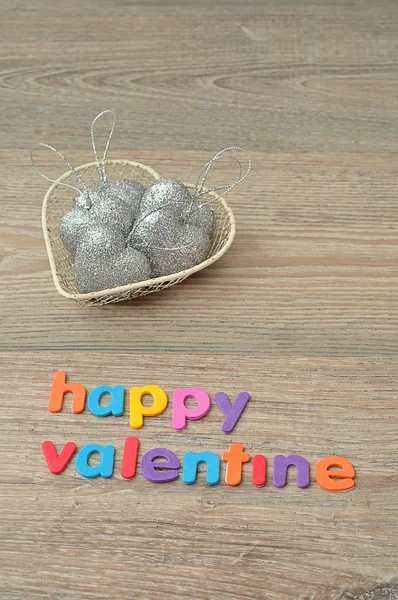 A wire basket filled with silver heart shape baubles and the words happy valentine — Stock Photo, Image