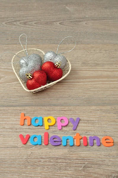 Una cesta de alambre llena de bolas de plata y corazón rojo y las palabras feliz San Valentín — Foto de Stock